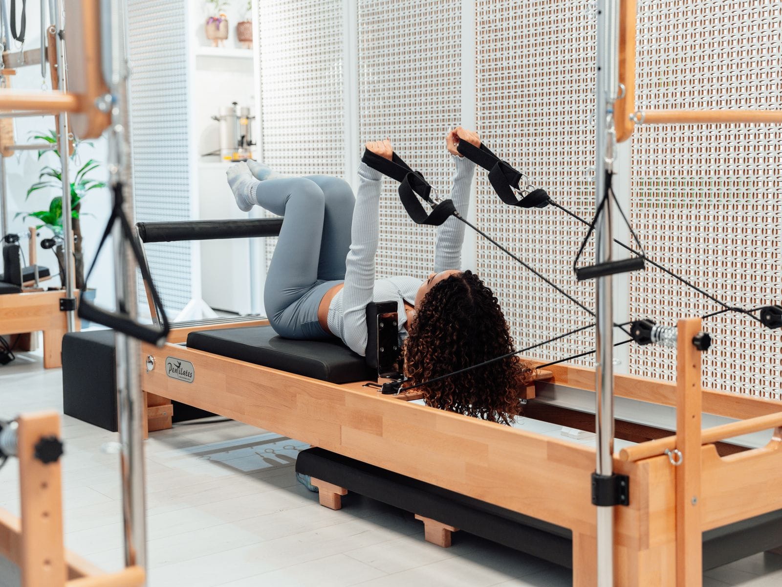 Aluna fazendo exercício com as alças no aparelho de Pilates